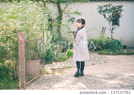 Girl holding a basket of vegetables in the garden Girl holding a basket of vegetables in the garden 137537761