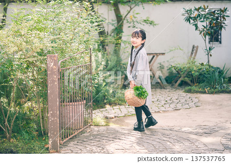 Girl holding a basket of vegetables in the garden 137537765