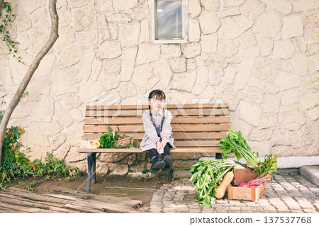 Girl sitting on a bench with vegetables 137537768