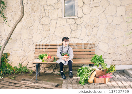 Girl sitting on a bench with vegetables 137537769