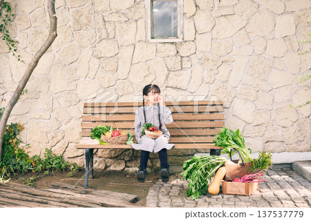 Girl sitting on a bench with vegetables 137537779
