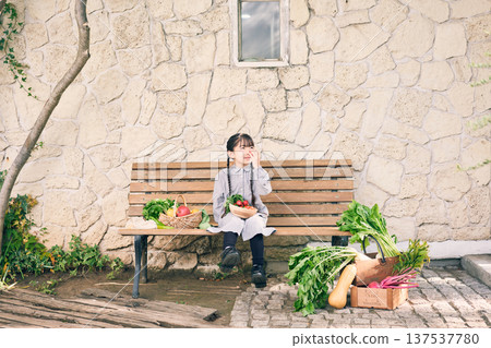 女孩坐在長椅上,旁邊放著蔬菜 女孩坐在長椅上,旁邊放著蔬菜 137537780