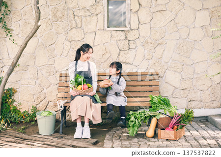 Parents and children sitting on a bench holding vegetables 137537822