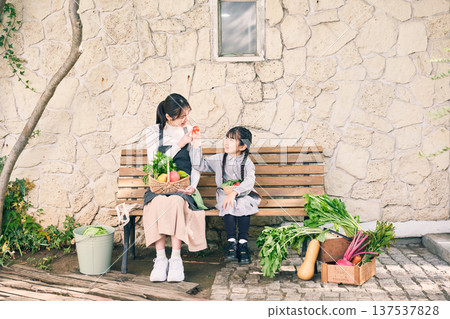 父母和孩子坐在長椅上，手裡拿著蔬菜 137537828