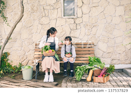 Parents and children sitting on a bench holding vegetables Parents and children sitting on a bench holding vegetables 137537829