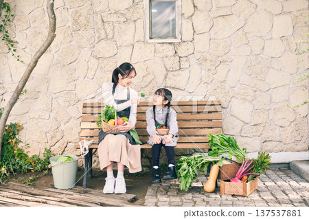 父母和孩子坐在長椅上，手裡拿著蔬菜 137537881