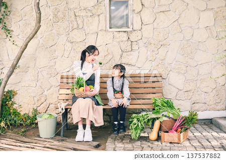 Parents and children sitting on a bench holding vegetables Parents and children sitting on a bench holding vegetables 137537882
