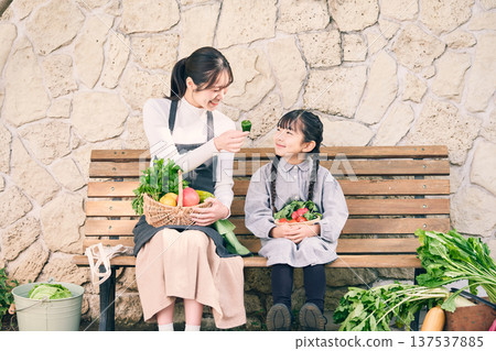 Parents and children sitting on a bench holding vegetables 137537885