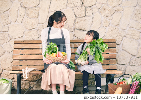 Parents and children sitting on a bench holding vegetables Parents and children sitting on a bench holding vegetables 137537911