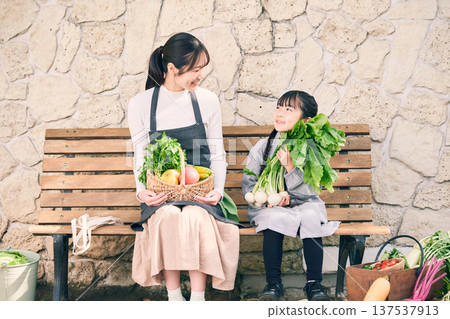 Parents and children sitting on a bench holding vegetables Parents and children sitting on a bench holding vegetables 137537913