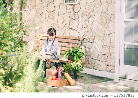 Girl sitting on a bench holding vegetables 137537932