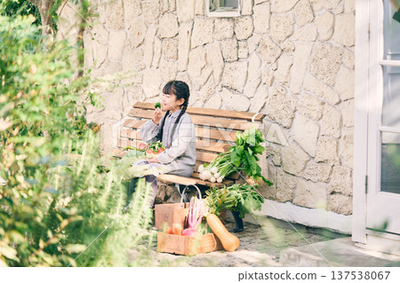 Girl sitting on a bench holding vegetables Girl sitting on a bench holding vegetables 137538067