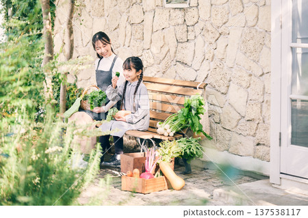 Parents and children sitting on a bench holding vegetables 137538117