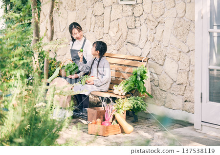 Parents and children sitting on a bench holding vegetables Parents and children sitting on a bench holding vegetables 137538119