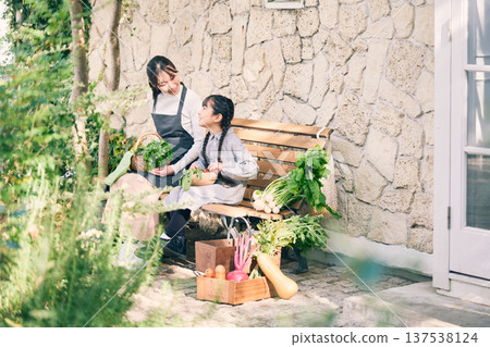 Parents and children sitting on a bench holding vegetables 137538124