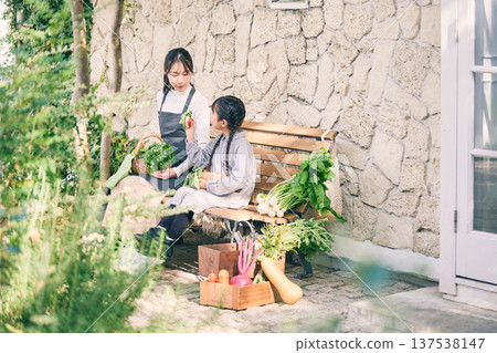 Parents and children sitting on a bench holding vegetables 137538147