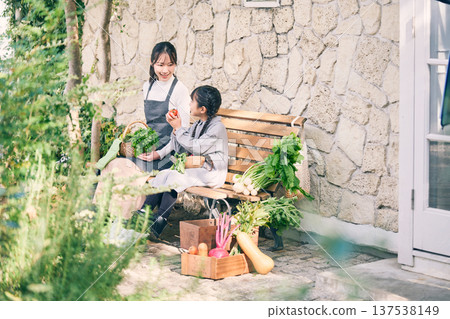 Parents and children sitting on a bench holding vegetables 137538149