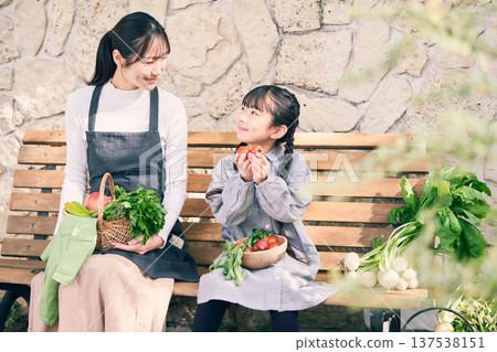 Parents and children sitting on a bench holding vegetables 137538151