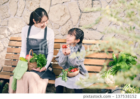 父母和孩子坐在長椅上，手裡拿著蔬菜 137538152