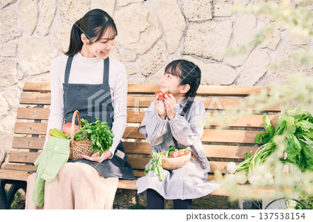 父母和孩子坐在長椅上，手裡拿著蔬菜 137538154