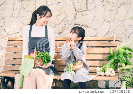 Parents and children sitting on a bench holding vegetables 137538168