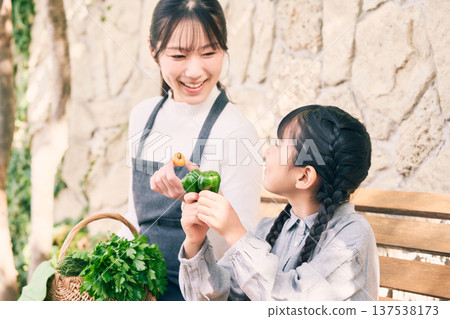 Parents and children sitting on a bench holding vegetables 137538173
