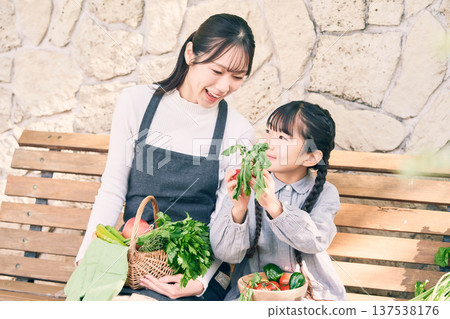 父母和孩子坐在長椅上，手裡拿著蔬菜 137538176