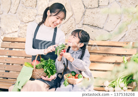 Parents and children sitting on a bench holding vegetables Parents and children sitting on a bench holding vegetables 137538208