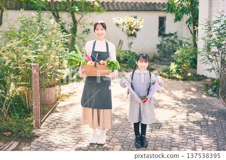 父母和孩子在花園裡拿著蔬菜 父母和孩子在花園裡拿著蔬菜 137538395