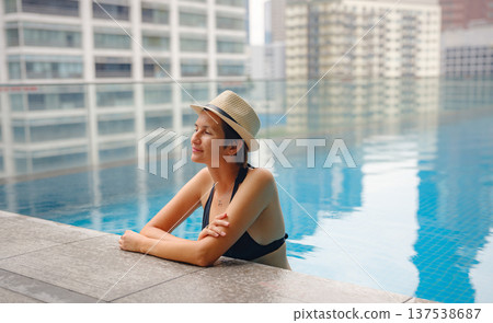 Young woman relaxing by the pool at a Kuala Lumpur hotel Young woman relaxing by the pool at a Kuala Lumpur hotel 137538687