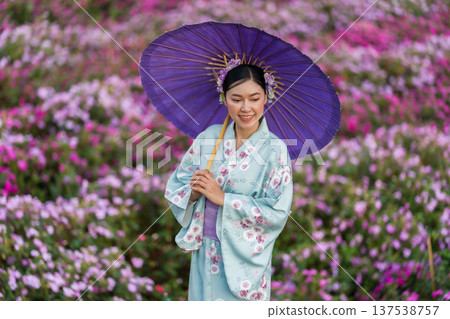 woman in yukata (kimono dress) holding umbrella with flower blooming in garden 137538757