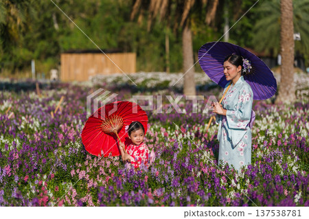 woman and child girl in yukata (kimono dress) walking with angelonia flower blooming in garden 137538781