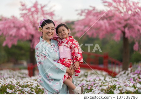 woman and child girl in yukata (kimono dress) with sakura flower or cherry blossom blooming in garden woman and child girl in yukata (kimono dress) with sakura flower or cherry blossom blooming in garden 137538786