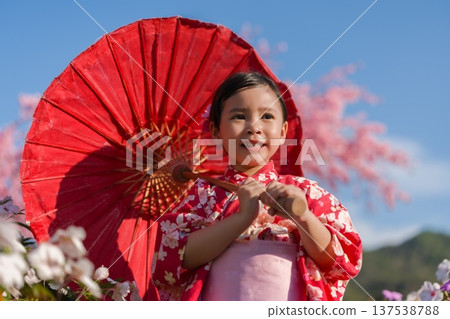 preschool child girl in yukata (kimono dress) holding umbrella with sakura flower or cherry blossom blooming in garden preschool child girl in yukata (kimono dress) holding umbrella with sakura flower or cherry blossom blooming in garden 137538788