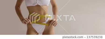 Sexy fitness diet banner with woman measuring slim waist with tape measure in white lingerie, weight loss and healthy lifestyle concept with copy space 137539238