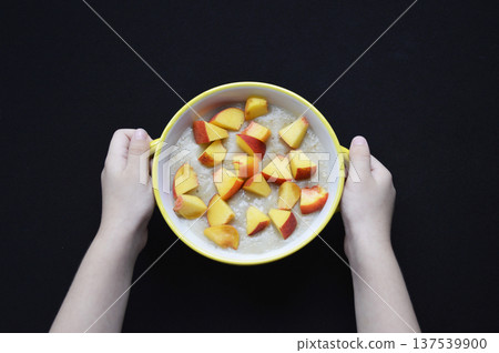 oatmeal cooked in milk with pieces of ripe peach in a bowl on a black background oatmeal cooked in milk with pieces of ripe peach in a bowl on a black background 137539900