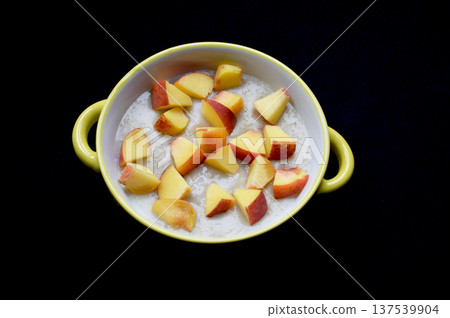oatmeal cooked in milk with pieces of ripe peach in a bowl on a black background oatmeal cooked in milk with pieces of ripe peach in a bowl on a black background 137539904