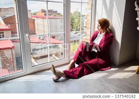 Quietly seated woman by window assesses future strategies with focus Quietly seated woman by window assesses future strategies with focus 137540182