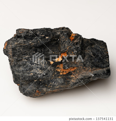 Raw Black Tourmaline Mineral Specimen With Orange Iron Oxide Streaks Displayed Against Clean White Background For Geology Study And Collection Raw Black Tourmaline Mineral Specimen With Orange Iron Oxide Streaks Displayed Against Clean White Background For Geology Study And Collection 137541131