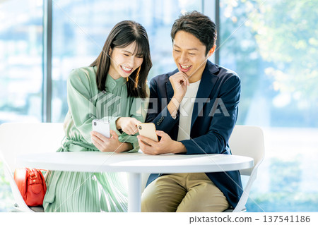 搜尋在智能手機的一對年輕夫婦 搜尋在智能手機的一對年輕夫婦 137541186