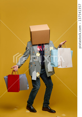 Shopper with cardboard box head carrying shopping bags 137541357