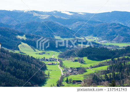 Vast green valleys and distant snow-capped mountains create a stunning panoramic view of the peaceful landscape during a bright spring day in the countryside Vast green valleys and distant snow-capped mountains create a stunning panoramic view of the peaceful landscape during a bright spring day in the countryside 137541743