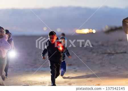 Kids running on beach at night with glowing light Kids running on beach at night with glowing light 137542145