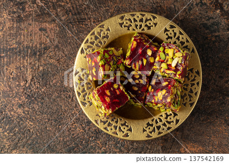 Turkish delights with pistachio in golden dish on a brown background. Turkish delights with pistachio in golden dish on a brown background. 137542169