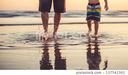 Father and child splashing water and walking in shallow sea at sunset for summer background and banner design Father and child splashing water and walking in shallow sea at sunset for summer background and banner design 137542301
