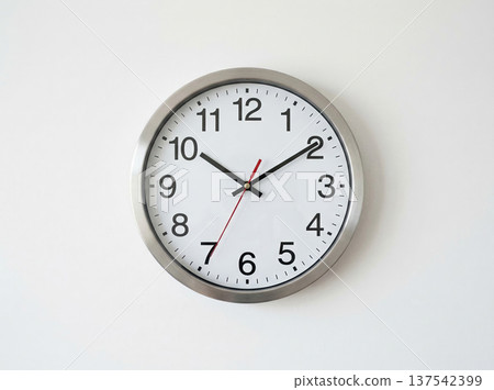 Round Analog Wall Clock with Metal Frame Displaying Current Time Against White Background Round Analog Wall Clock with Metal Frame Displaying Current Time Against White Background 137542399