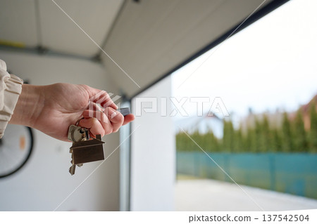 Hand holding keys near open garage door. Concept of home ownership Hand holding keys near open garage door. Concept of home ownership 137542504