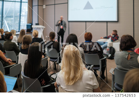 Business seminar with speaker presenting to engaged audience in modern conference room setting Business seminar with speaker presenting to engaged audience in modern conference room setting 137542653