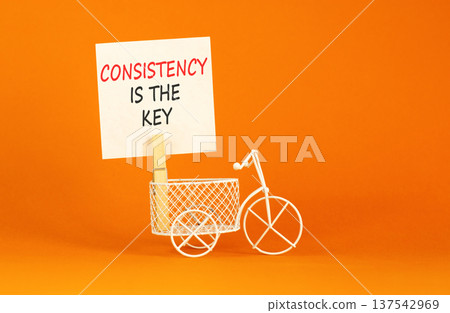 Consistency is the key symbol. Concept words Consistency is the key on beautiful white paper. Beautiful orange background. Miniature bicycle. Business consistency is the key concept. Copy space. 137542969