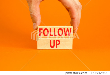 Follow up symbol. Concept word Follow up on beautiful wooden blocks. Beautiful orange paper background. Businessman's hand. Business follow up concept. Copy space. Follow up symbol. Concept word Follow up on beautiful wooden blocks. Beautiful orange paper background. Businessman's hand. Business follow up concept. Copy space. 137542986